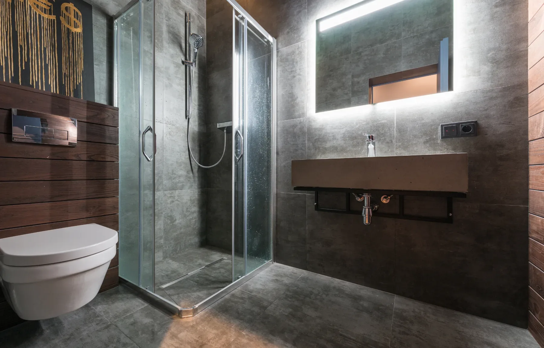 A modern, moodily lit bathroom features dark charcoal-gray tile walls and a wall-hung white toilet with a chrome flush plate